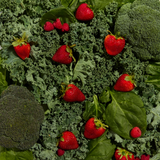 Strawberries and broccoli on a bed of green leafy vegetables