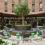 Outdoor courtyard with chairs, tables, and a tree in front of a building.