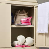 Beige locker with boxing gloves, pink bags, and a white towel inside.