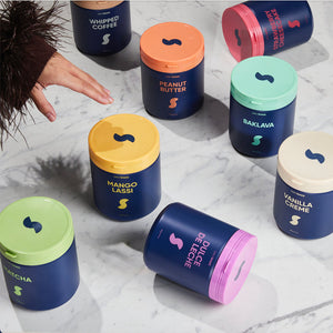 Assorted containers with colorful lids on a marble surface